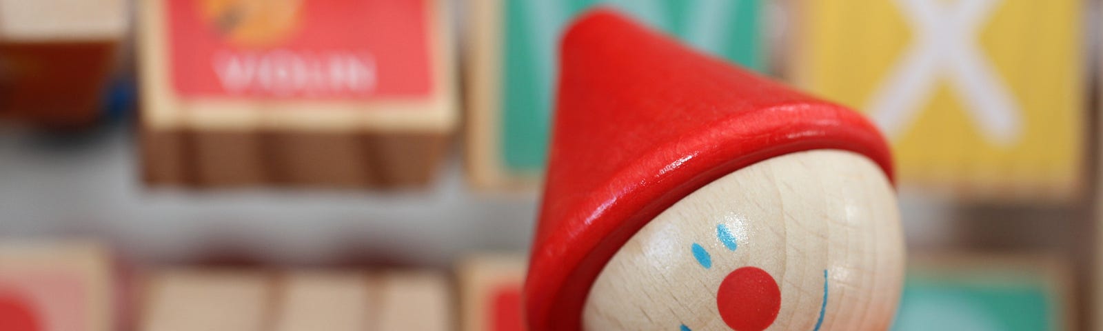 close up wooden colorful clown toy with wooden blocks in the background