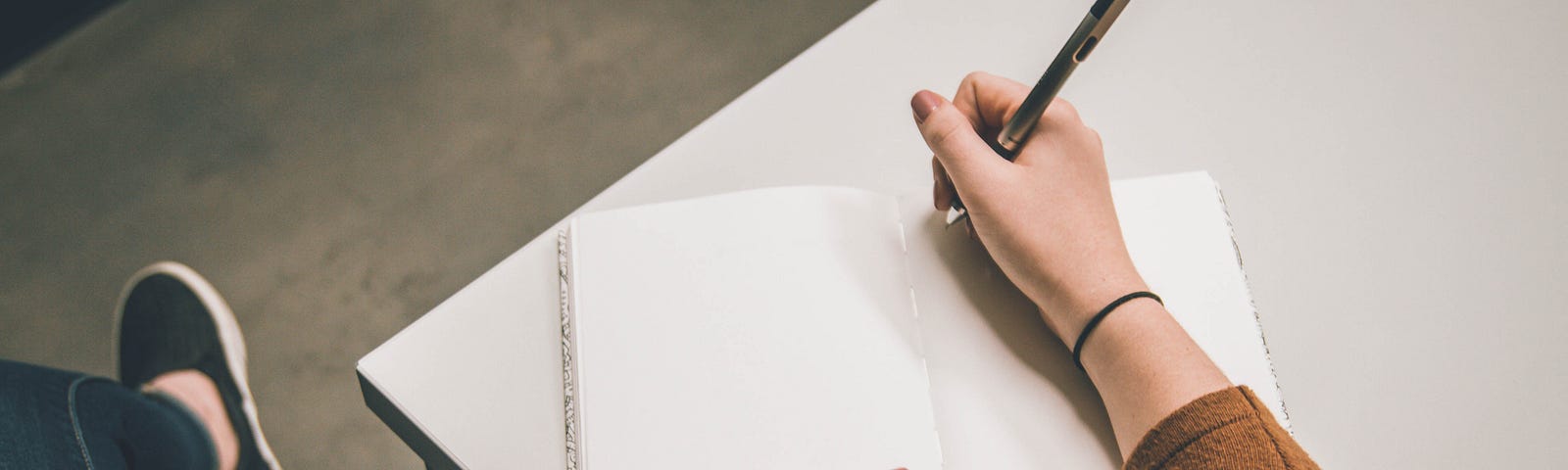 person writing in blank journal