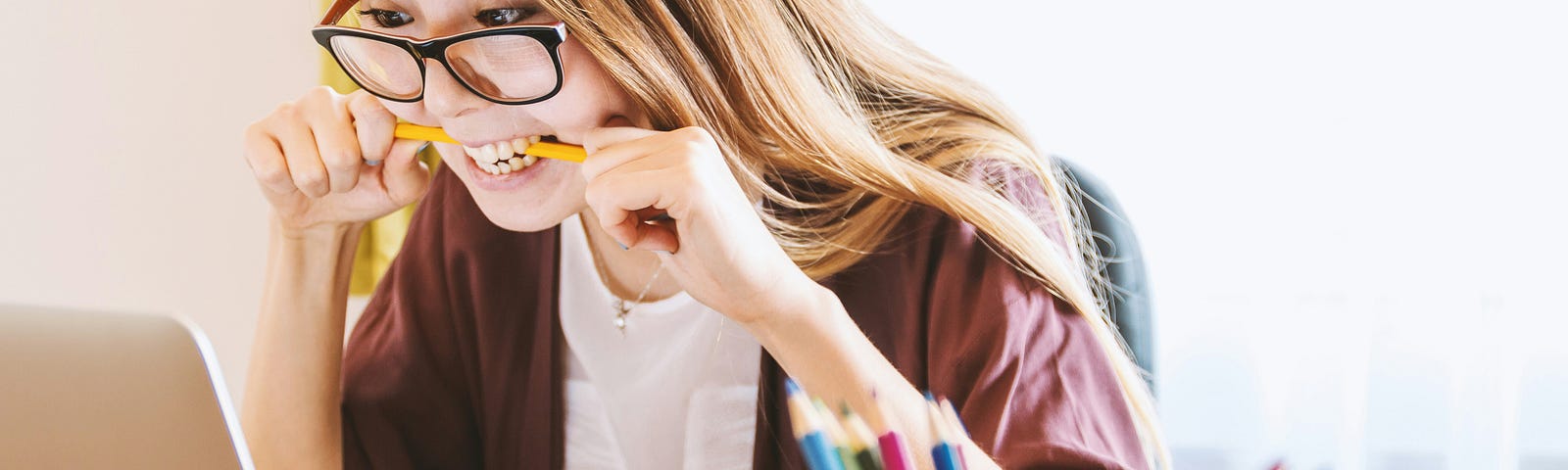 woman biting pencil looking at laptop with worry