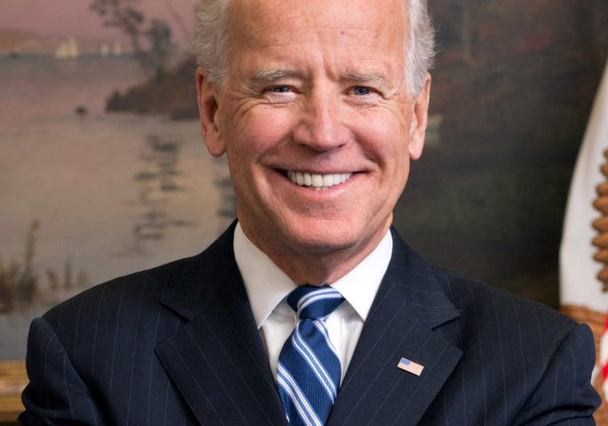 Official photo of President Joe Biden in a black suit and blue and white-stripped tie.