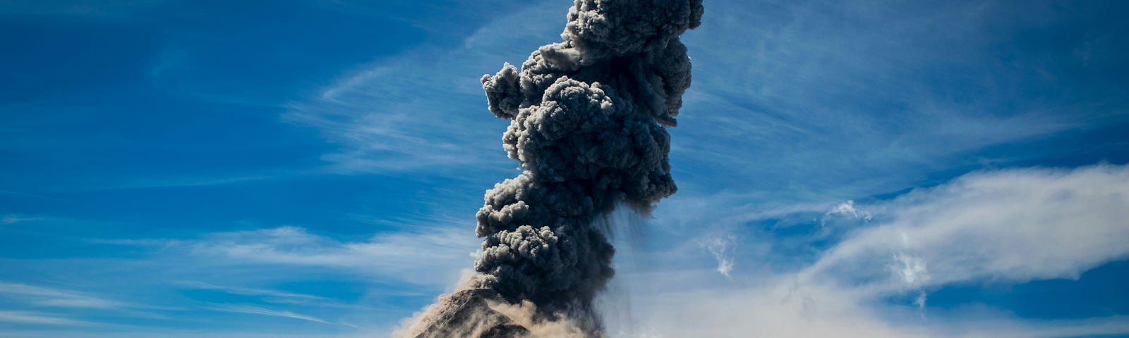 a moutain erupting; active volcano against the blue sky