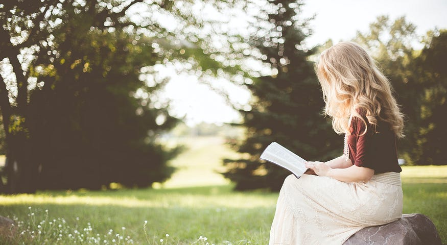 A girl sitting and reading in a garden