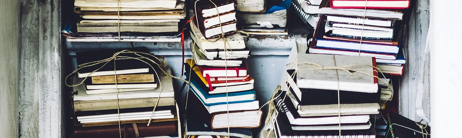 An open closet with stacks of journals tied with binding on the shelves.