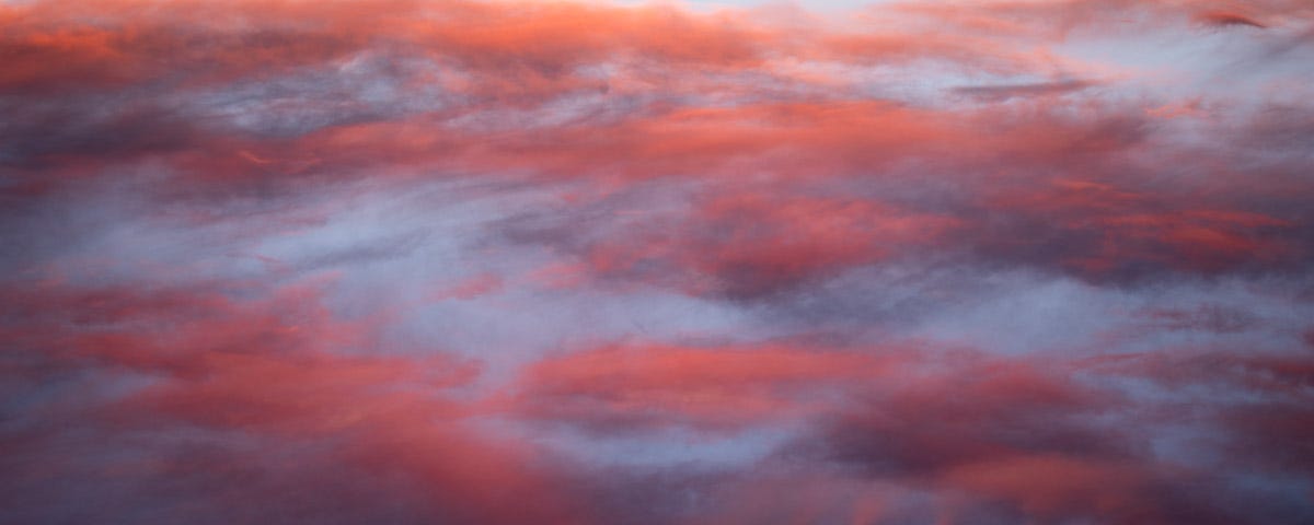 Pink sunset clouds against a blue background.