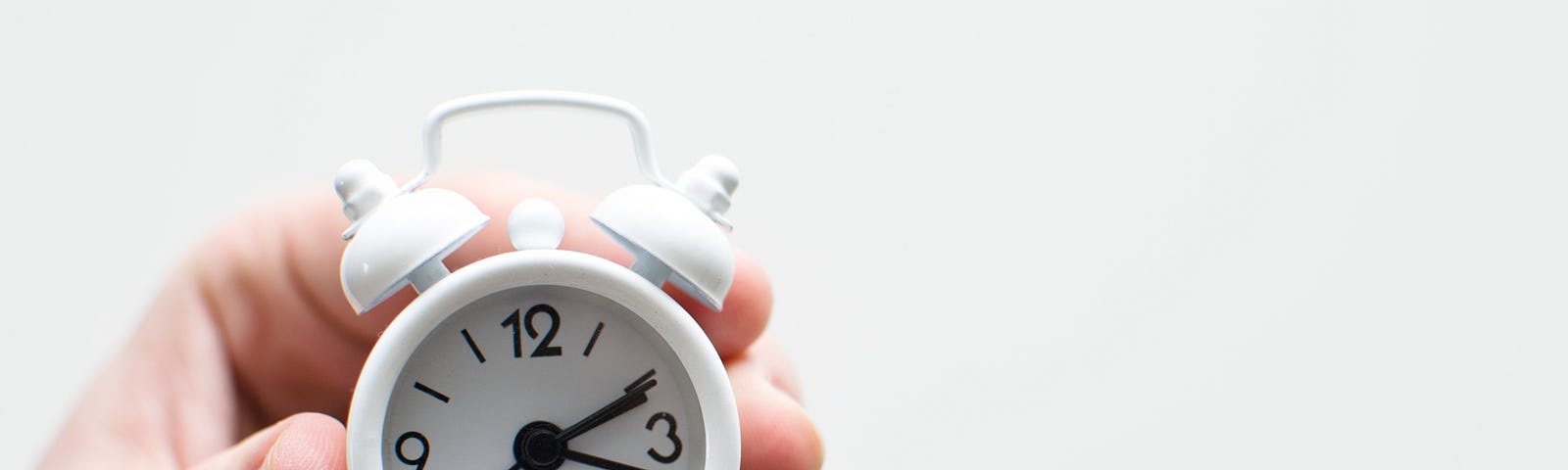 A tiny white clock in someone’s hand