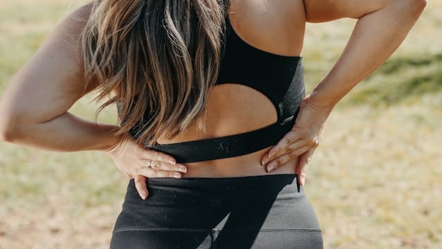 A lady holding her lower back, likely because of pain.