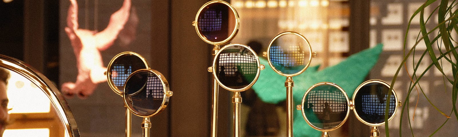 A glasses shop window of standing magnifying glasses on different height stands reflecting in shadow different angles of 2 people.