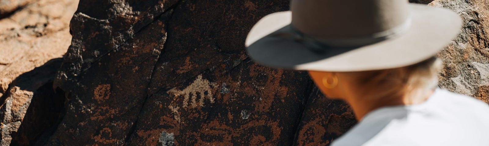 In the NEOM region, several rock carvings depict camels in various sizes and styles, and at varying levels of detail. Here we see dromedary camel observed by a woman with a hat.