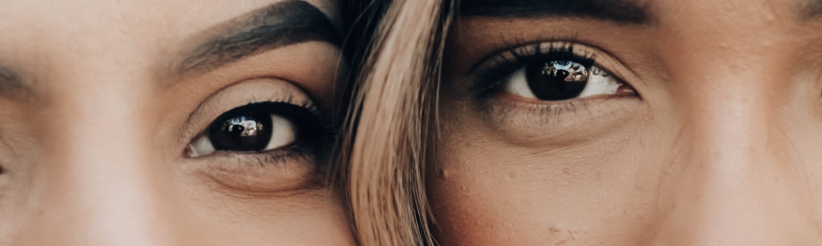 Two female friends up close, cheek to cheek.