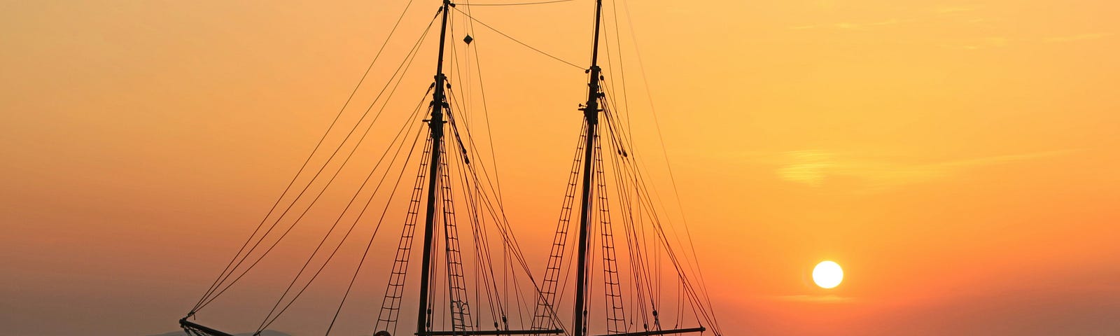 An orange sky as the sun sets over the calm waters. A lone ship that only hours later will hit the rocky coastline.