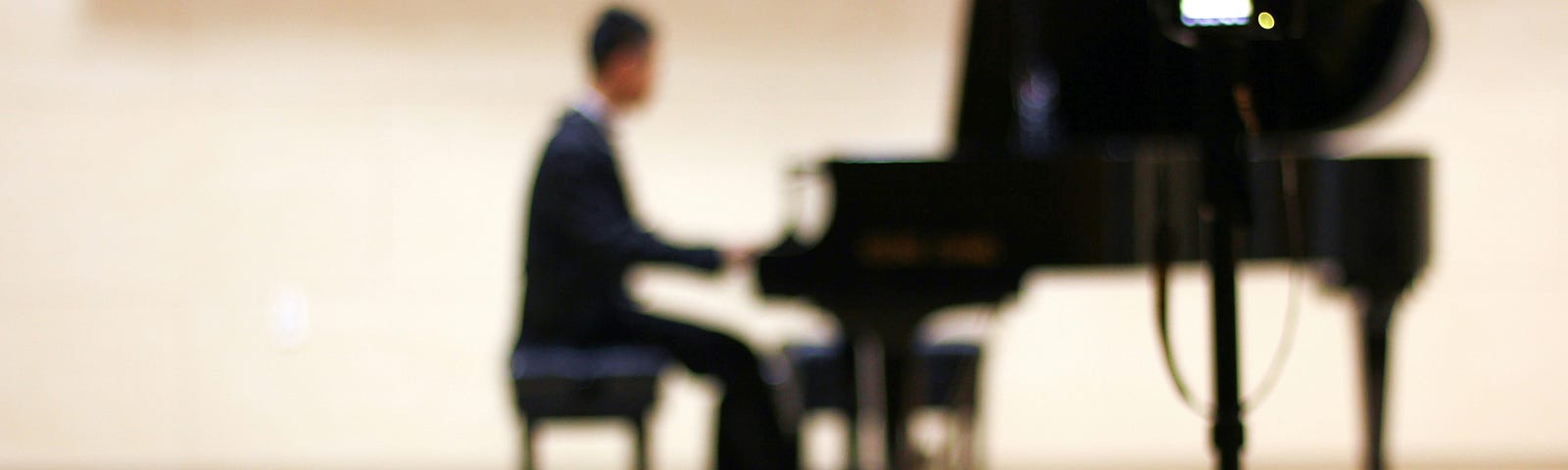 A person plays a grand piano on a stage.