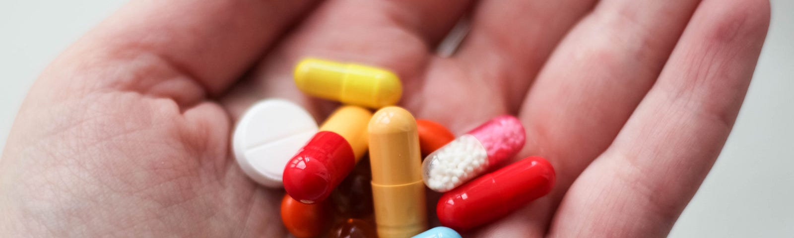 A palm holding a pile of multicoloured tablets and pills