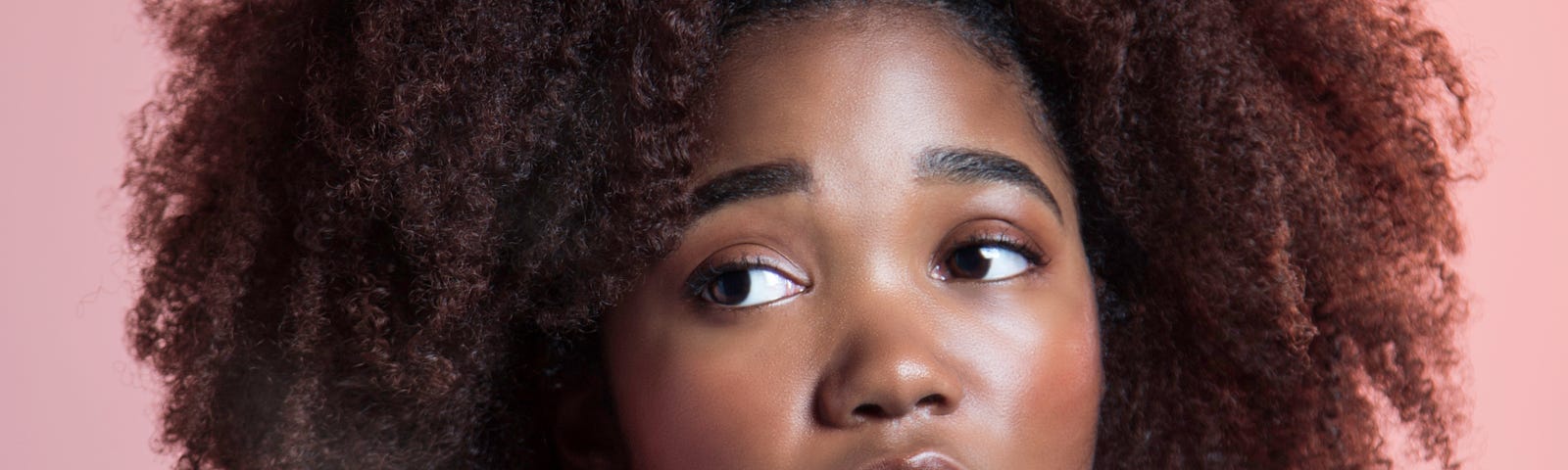 Black woman looking innocent and gentle while staring off to the side.