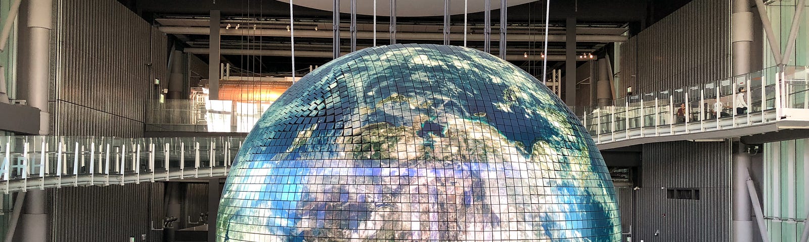 A globe hangs in an exhibition space.