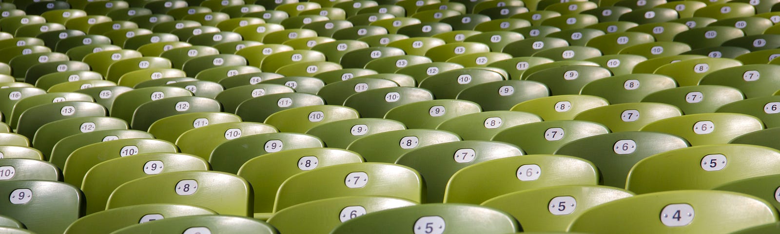 Rows of bright green auditorium seats with numbers on the back.