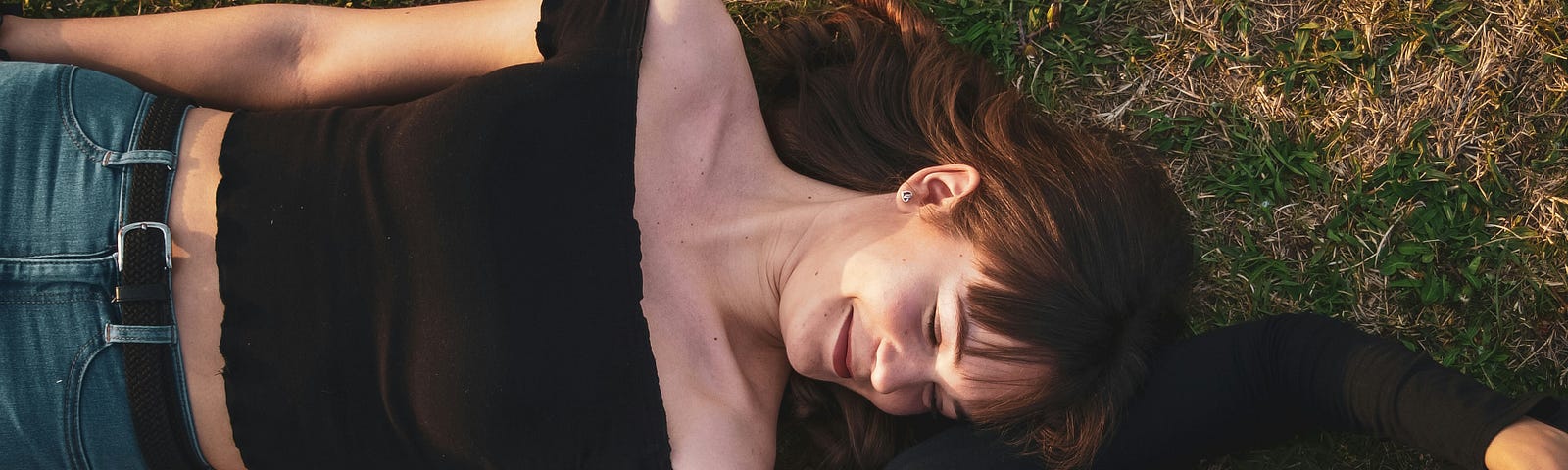 Mother-daughter duo, lying in the grass. Smiling at each other. Photo by Bence Halmosi on Unsplash