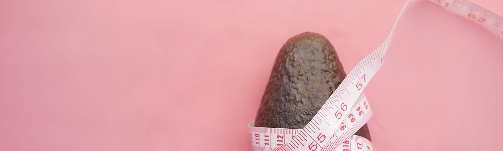 An avocado with a flexible measuring tape wrapped around it.