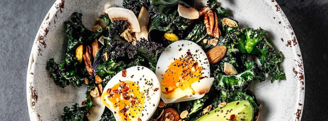 A salad with kale, avocado, and eggs.