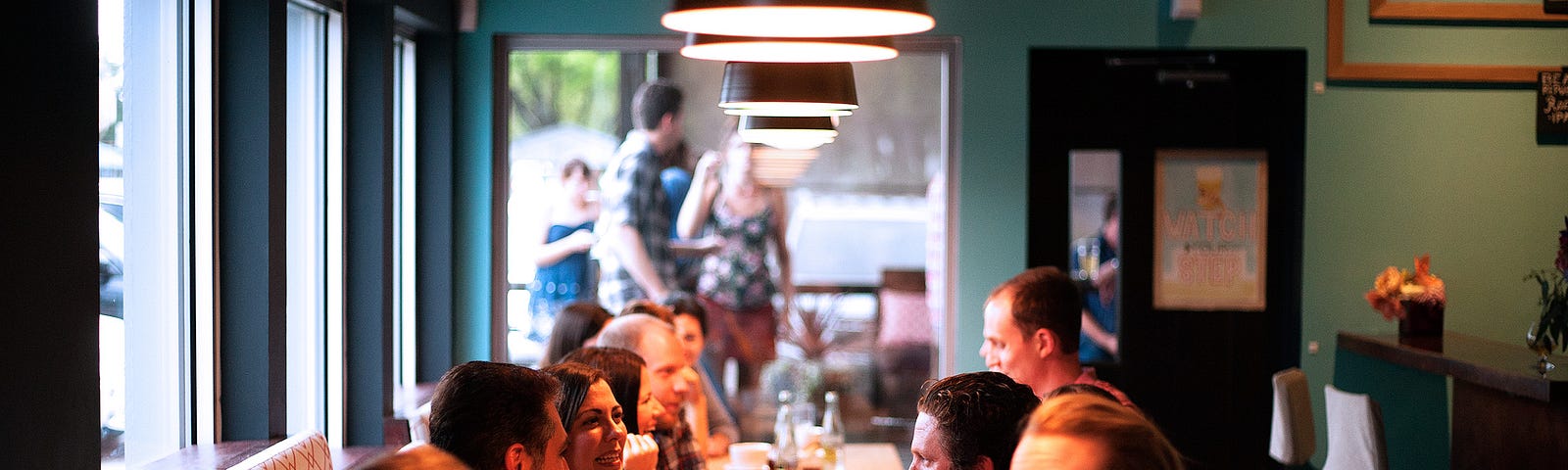 A group of people sitting with drinks at a large table in a restaurant.