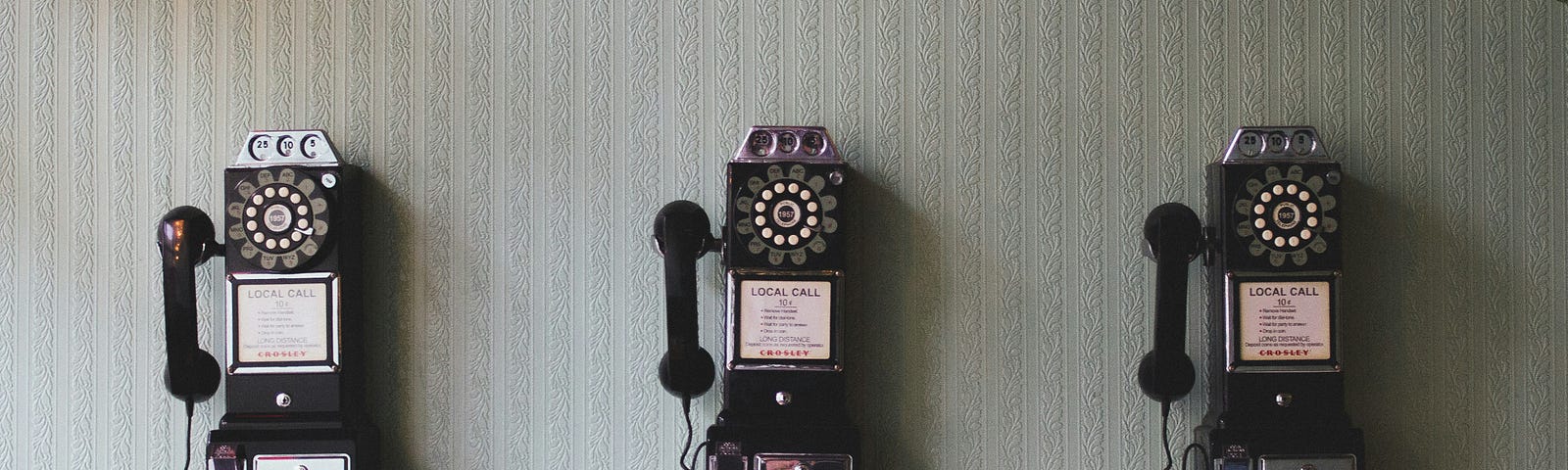 This is a photo of 3 old fashioned coin telephones