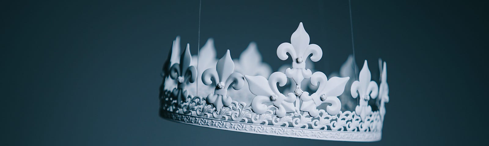 A regal-looking silver crown is suspended in the air by scarcely visible strings