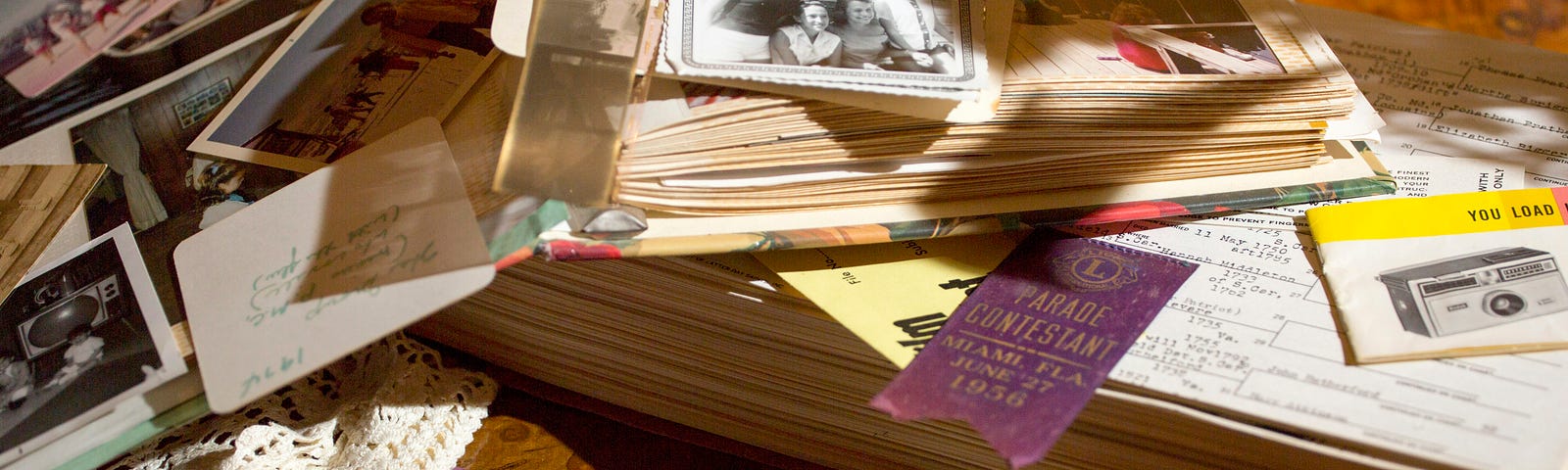 A pile of photos sits upon a scrapbook.