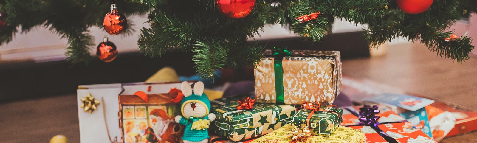 Wrapped Christmas presents sit under a Christmas tree.