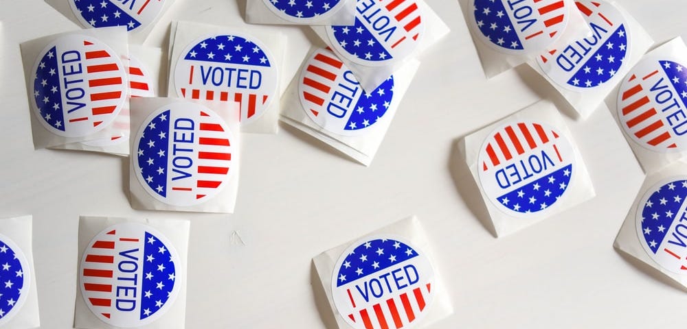Several red, white and blue voting stickers scattered on a white background.