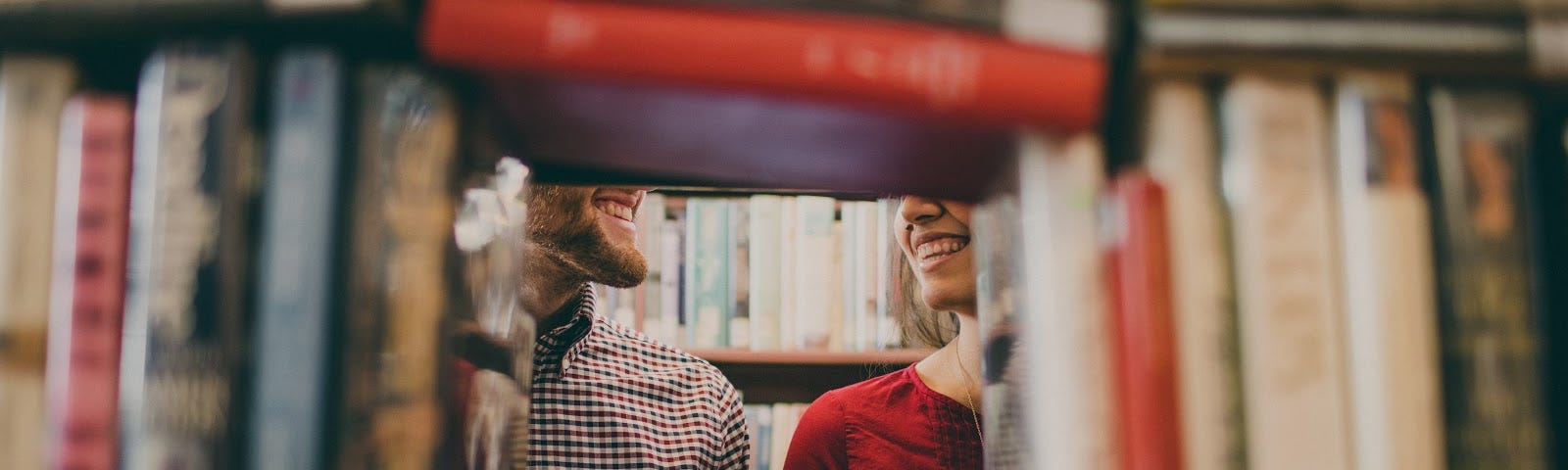 Image of couple smiling framed through a hidden hole in a bookshelf.