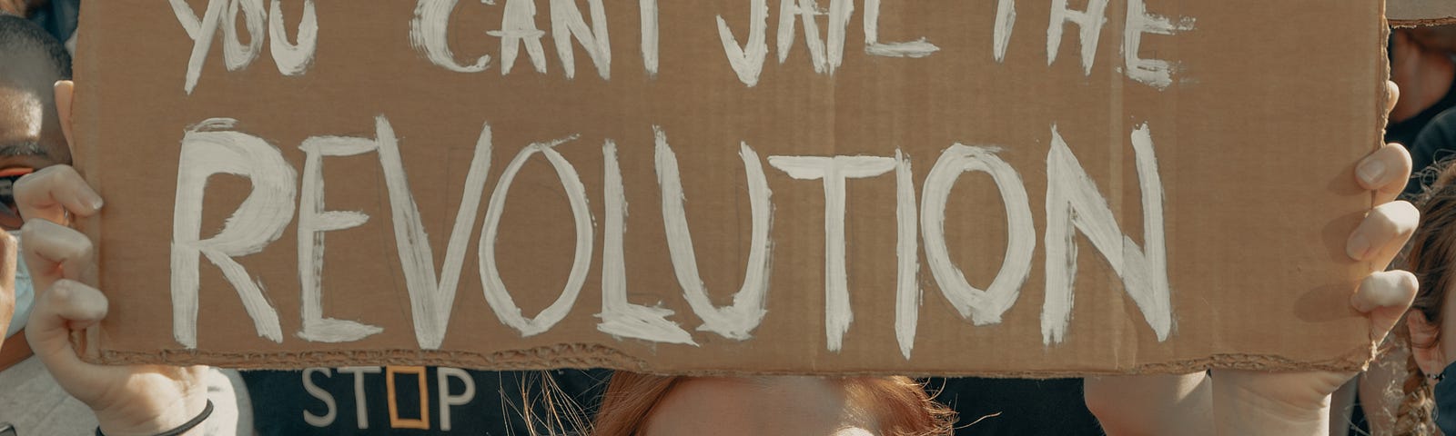 A protestor holding a sign, “ You can jail the revolutionary but you can’t jail the revolution”