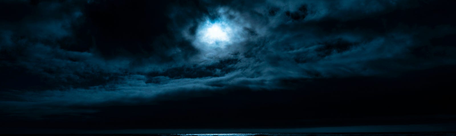 moon light peeking out from behind the clouds- you can see the white over water