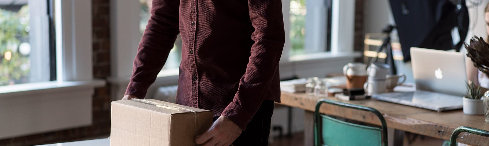 An artist in his studio packing up a box on a worktable.