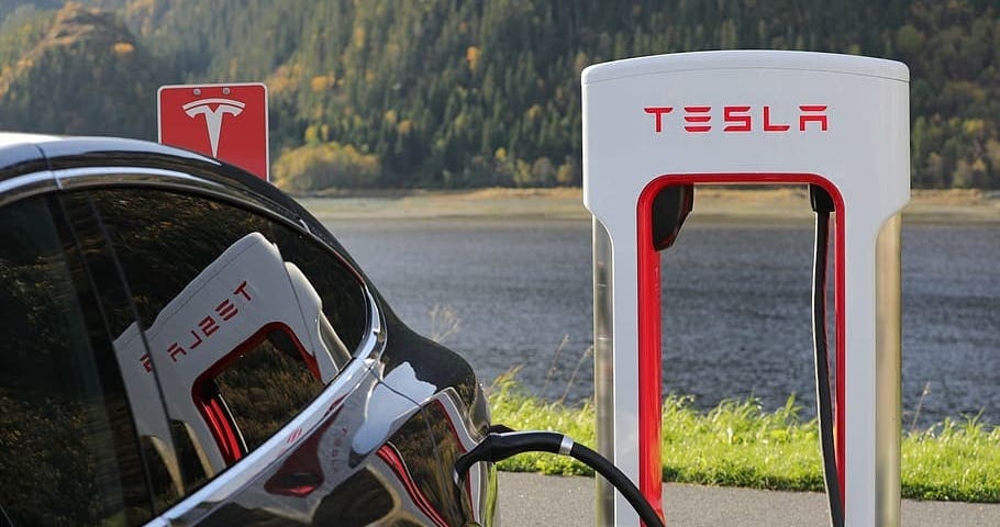 A electric car is charging next to one of the Tesla charging stations
