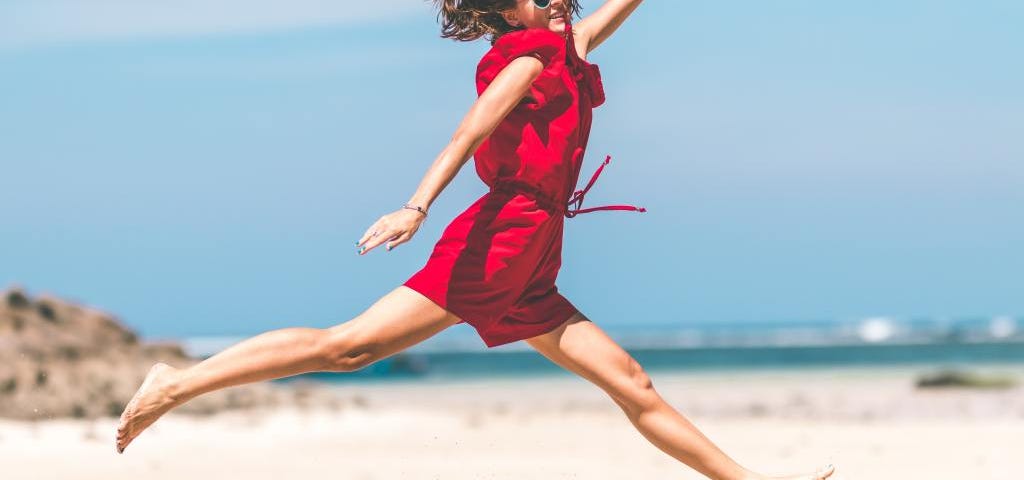 A woman jumping on the beach and achieving her goal