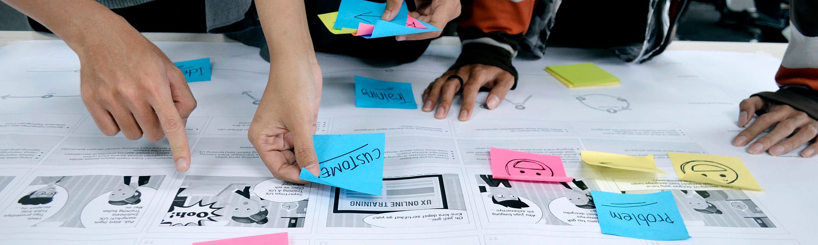 Three pair of hands are putting sticky notes onto notes laid on a table