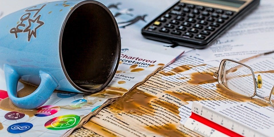 Overturned coffee mug and spilled coffee on business papers