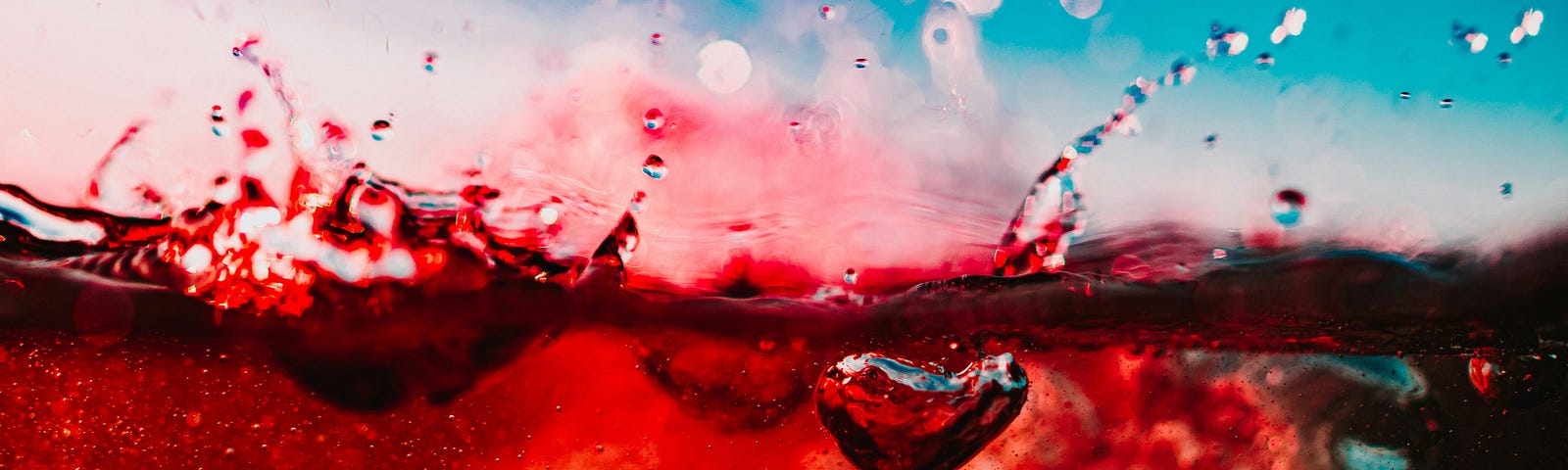 An extreme close up of a red liquid (perhaps wine) with some small splashes.