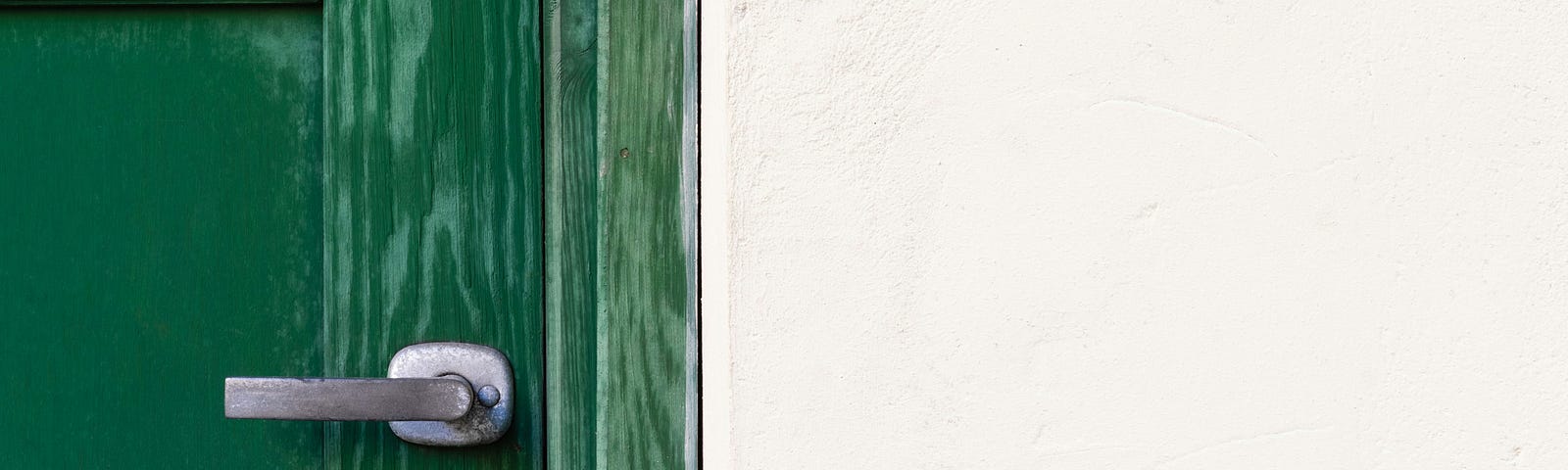 An outdoor photo of half a painted green door with handle and lock, next to the white siding of the house.