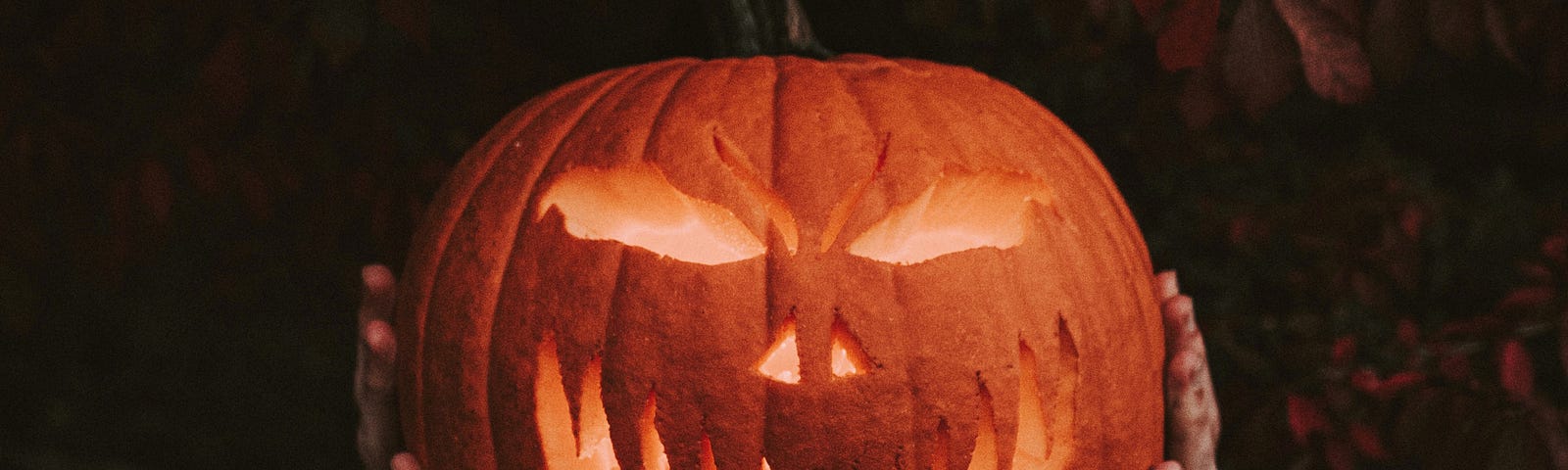 Man holding a jack o’lantern in front of his face
