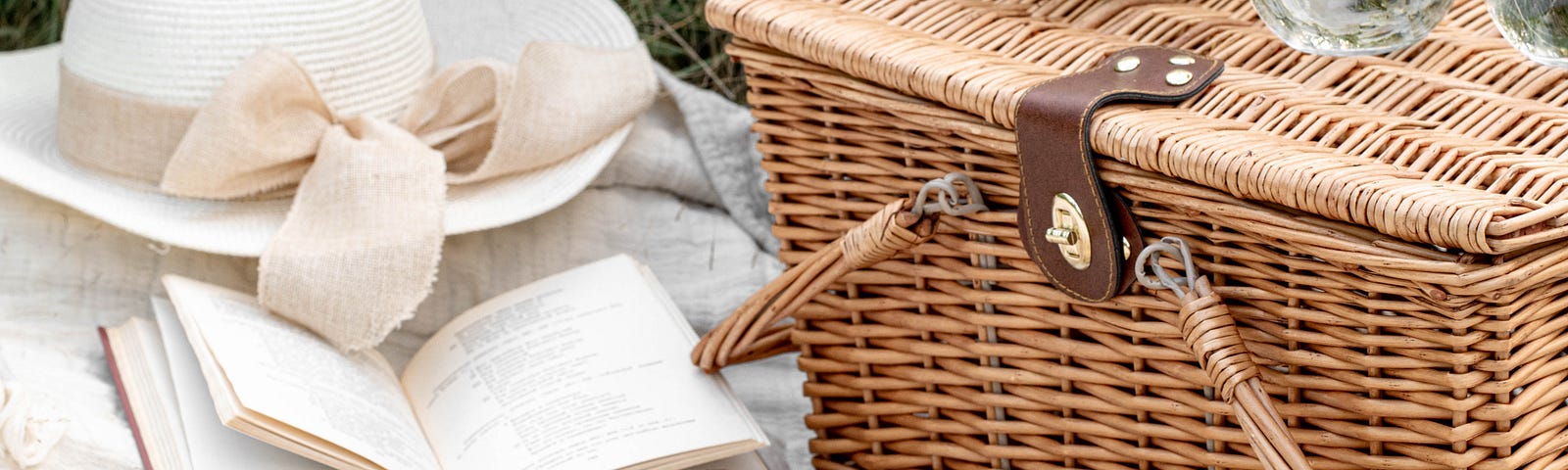 Picnic basket with a woman’s sun bonnet beside it, and a plate of cookies