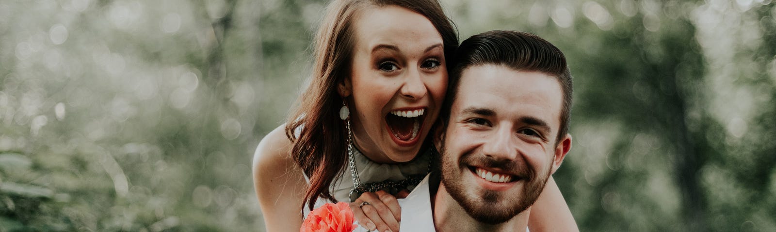 Happy couple smiling with girl holding red rose.