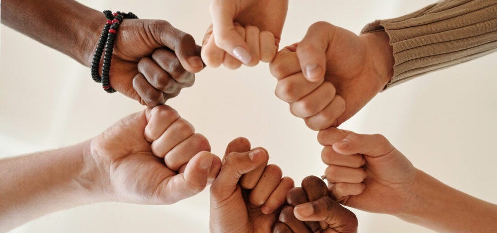 Six fits of diverse races joined together around a circle in solidarity