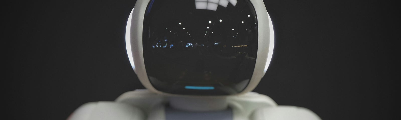 A toy-like robot faces the camera. Its face is a black screen similar to a computer monitor.