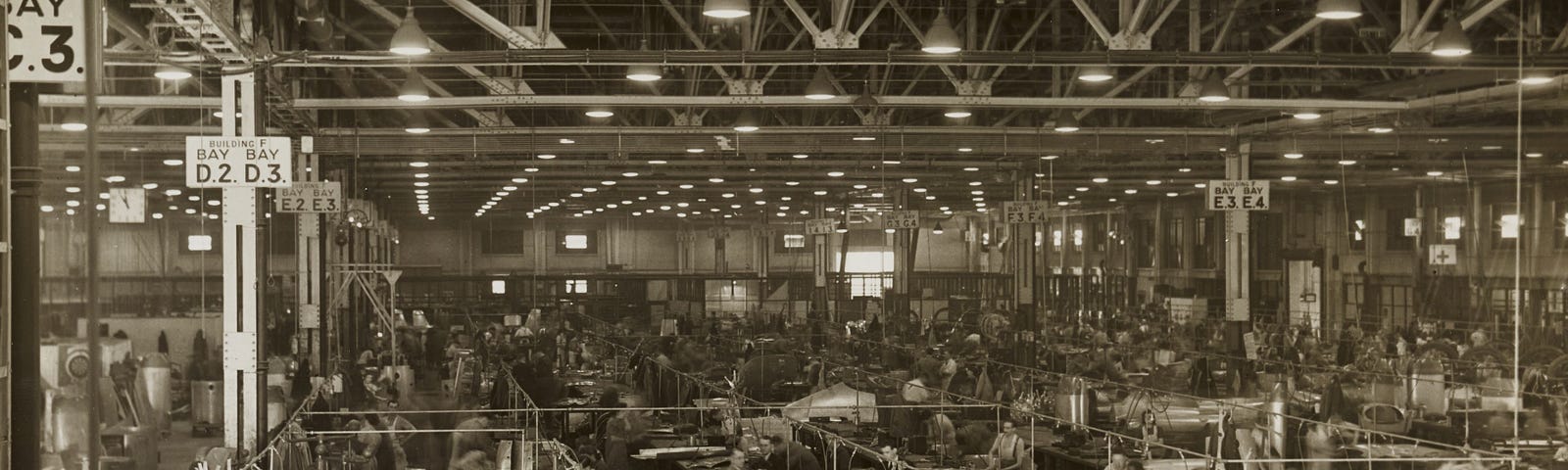 black and white image of workers in a large factory