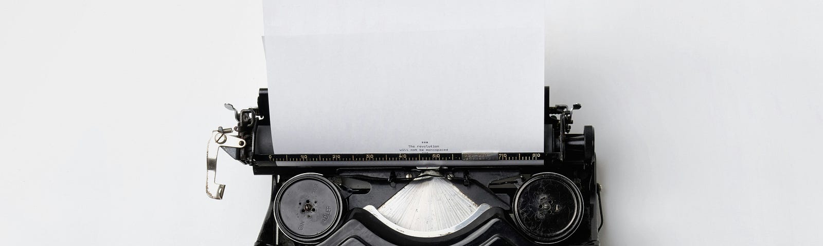 Black typewriter with a sheet of paper in it and a few words typed at the bottom of the page. White background