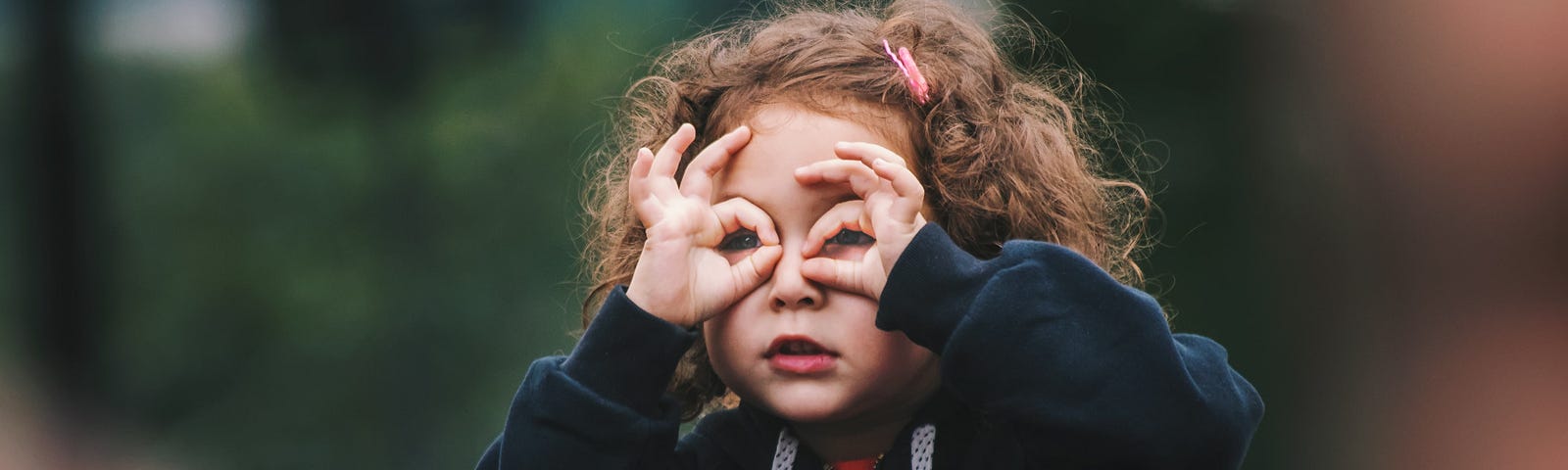 Young girl with hands positioned like glasses infront of her face