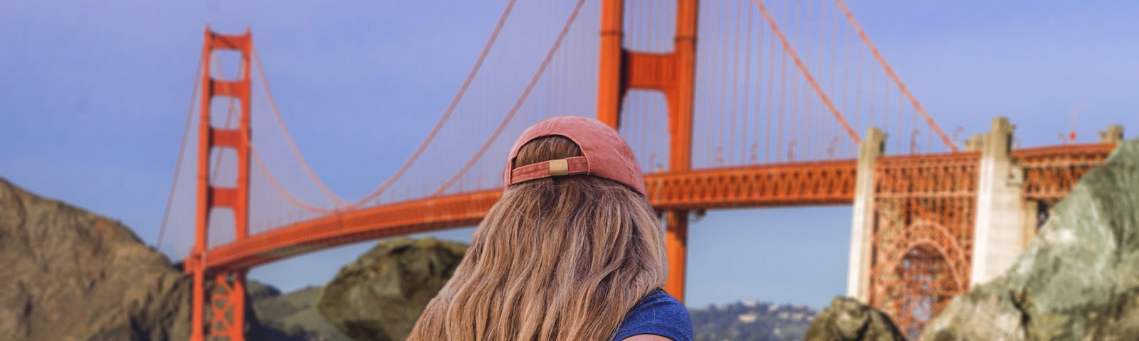 A lady is facing the Golden Gate Bridge holding someone’s hand and being reassured.