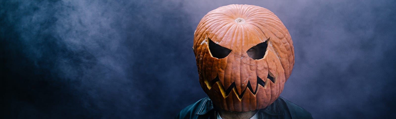 Man with pumpkin on head looking menacing.