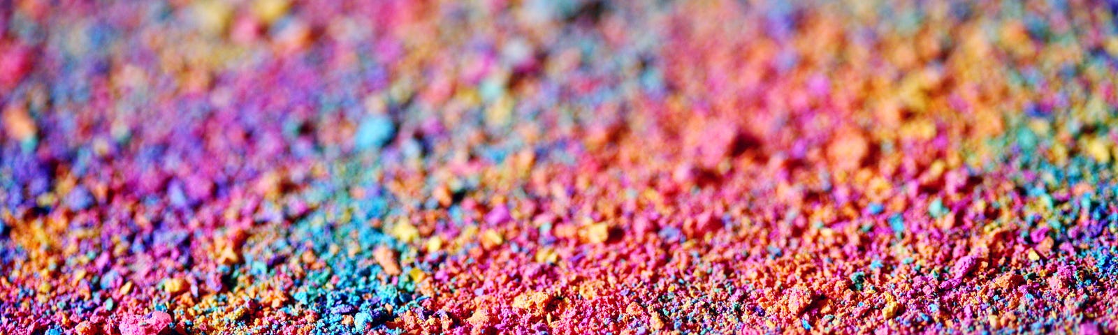 Various pastel colors arrayed like a rainbow of sand or grounded chalk strewn across a surface creating a random display of joyful colors.