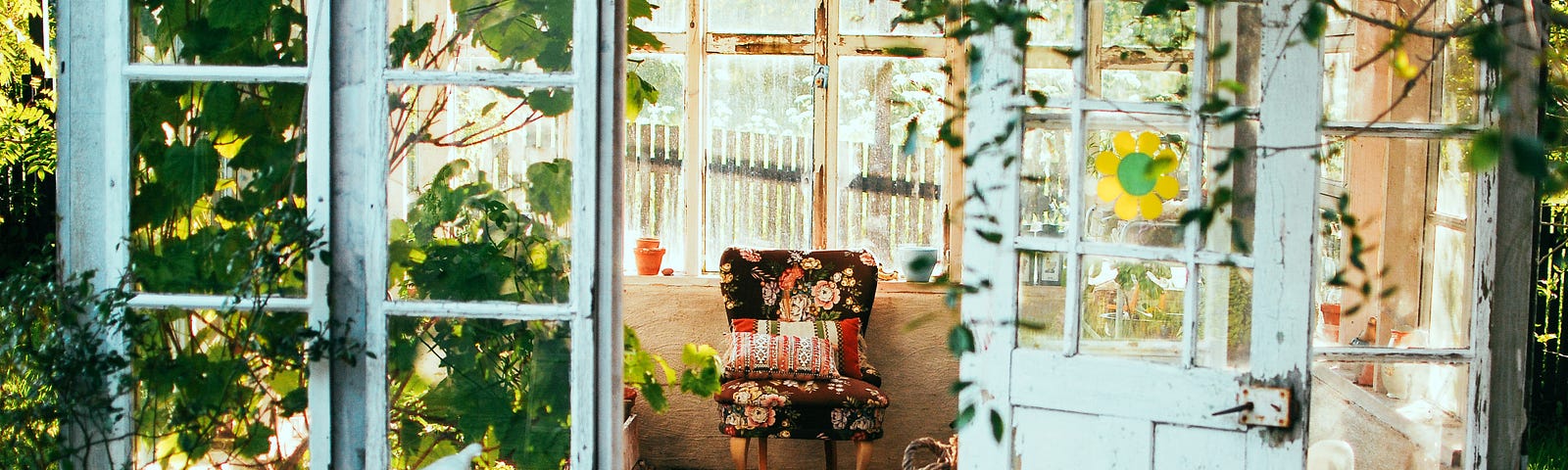 An English cottage conservatory, with a stuffed chair, covered in a black and red floral print.